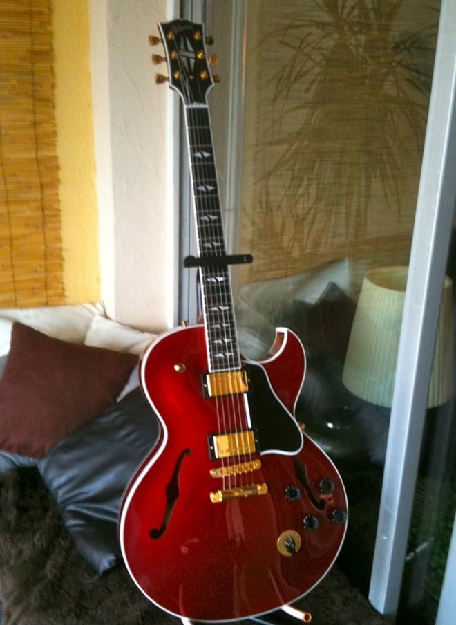 A red guitar leaning against a glass wall  AI-generated content may be incorrect.