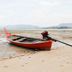 Sandy beach and boat in blue sky.